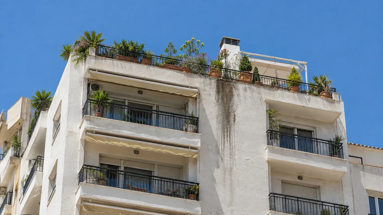 Mancha de humedad en la fachada bajo la terraza del ático de un edificio de apartamentos